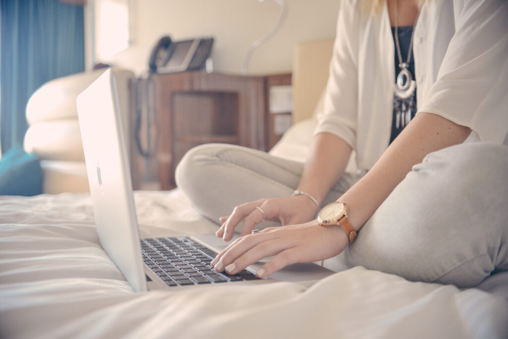 Een vrouw vergelijkt aanbieders op de energiemarkt terwijl ze op bed zit achter een laptop