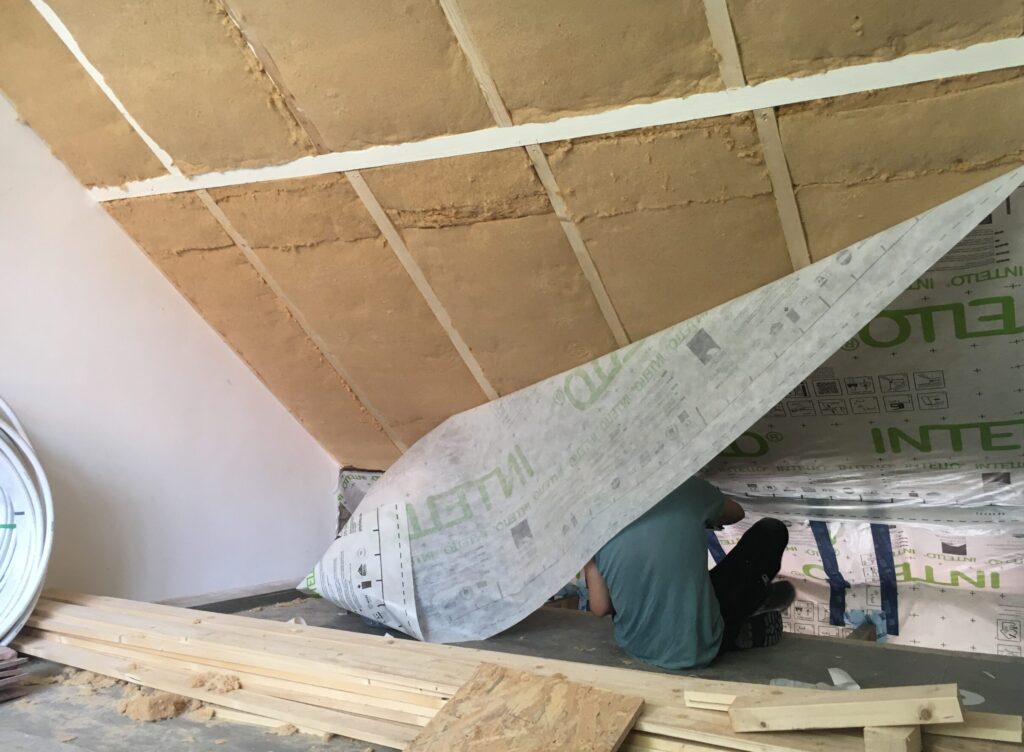 Platen houtvezelwol tegen de binnenkant van een schuin dak als natuurlijk isolatiemateriaal